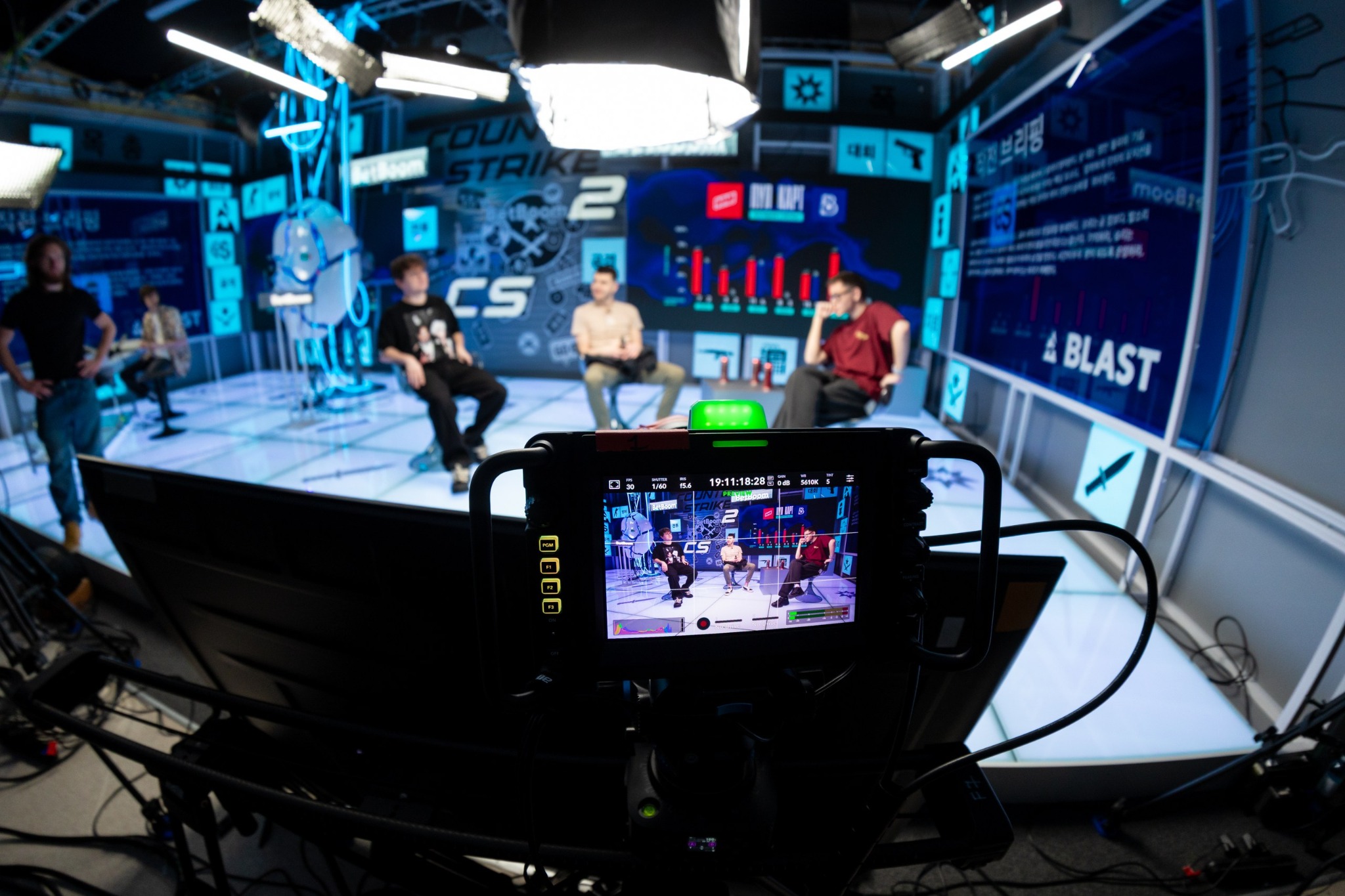 Camera monitor framing three hosts inside BLAST Studio