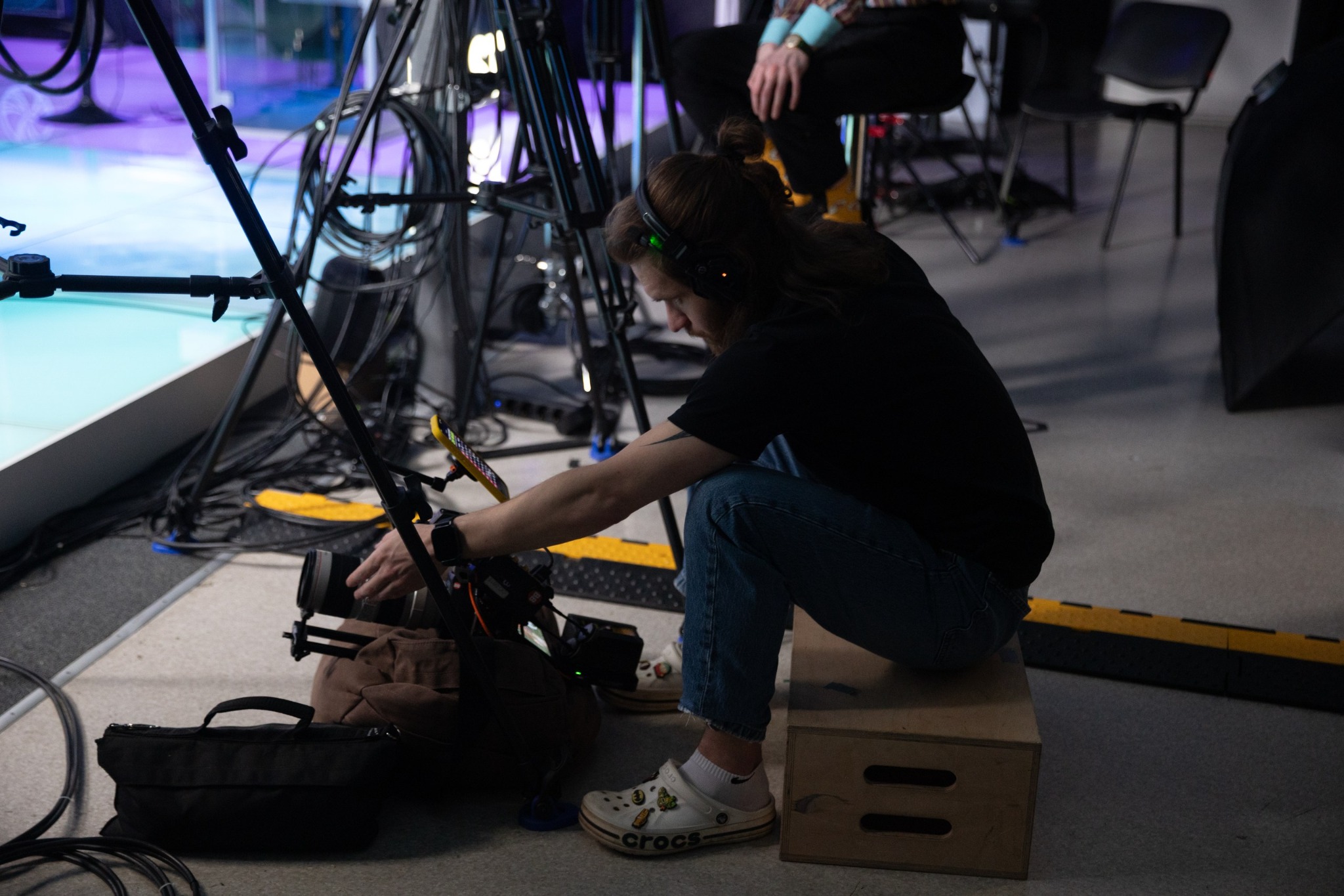 Crew member adjusting camera equipment on the BLAST Studio set