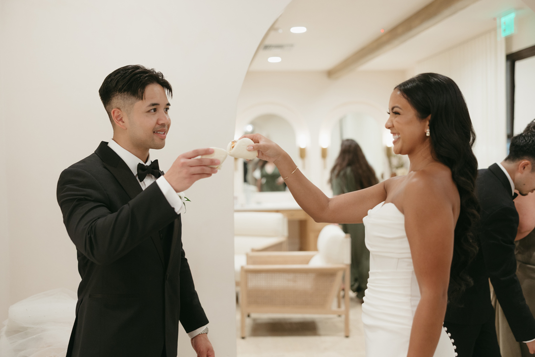 Bride and groom cheers with catered Bao cocktail hour appetizers inside the Serra Plaza Bridal Suite.