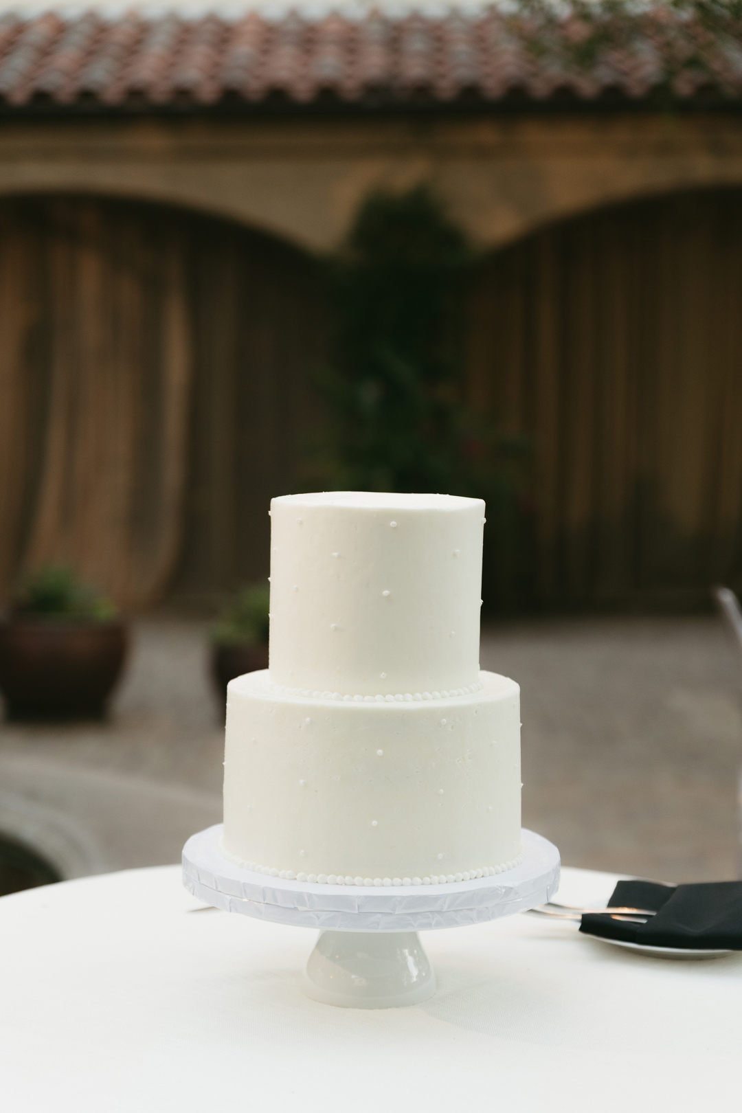 Two-tier wedding cake with dot ad scallop detailing.