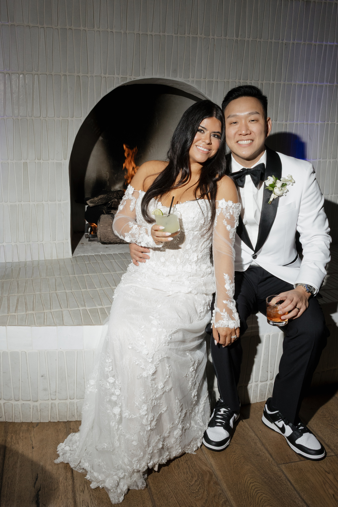 Bride and groom sip on signature drinks by the fireplace inside the Lounge at Serra Plaza during cocktail hour.