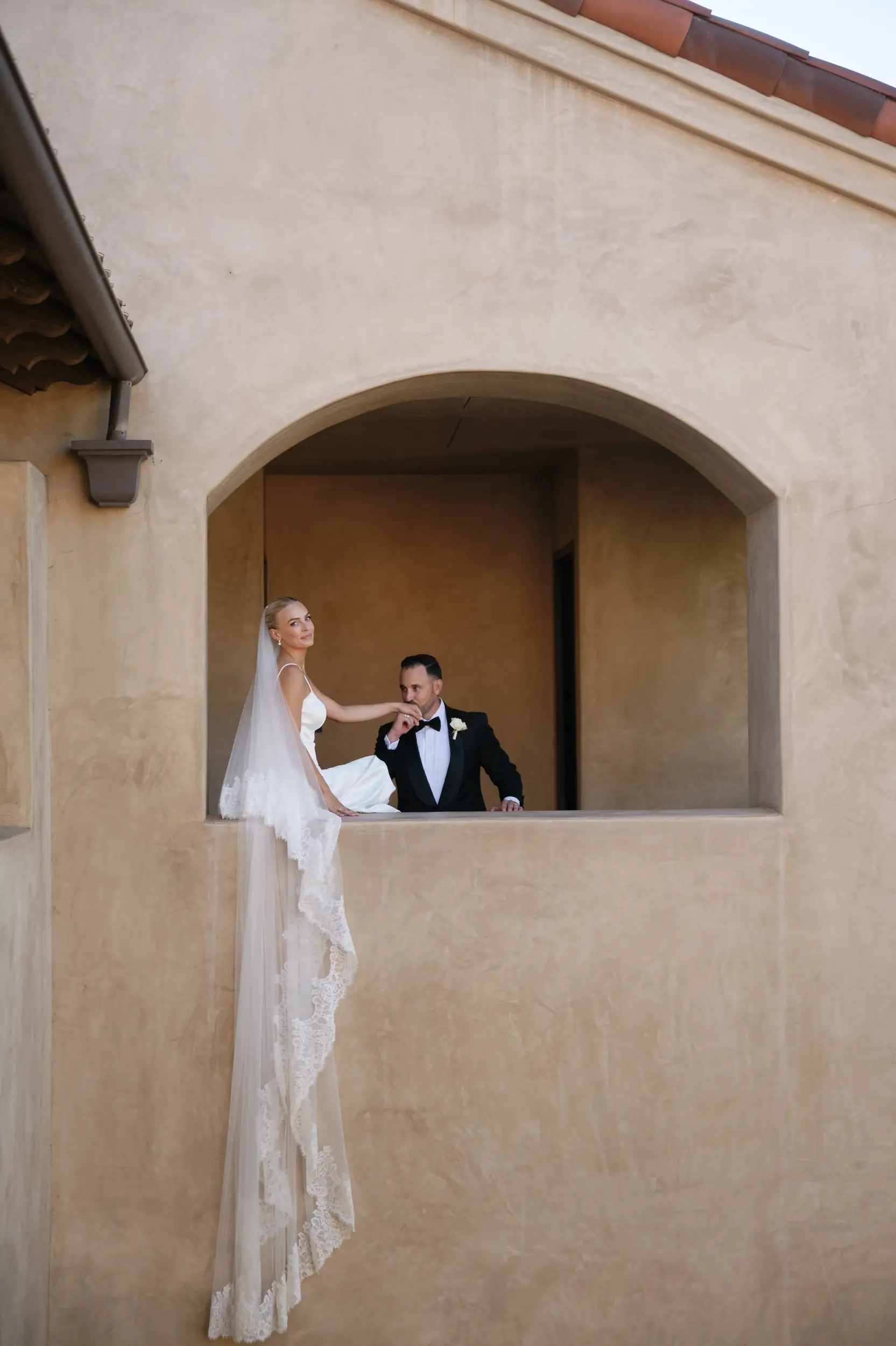 Bride sitting in venue window with veil draping down 2 stories.