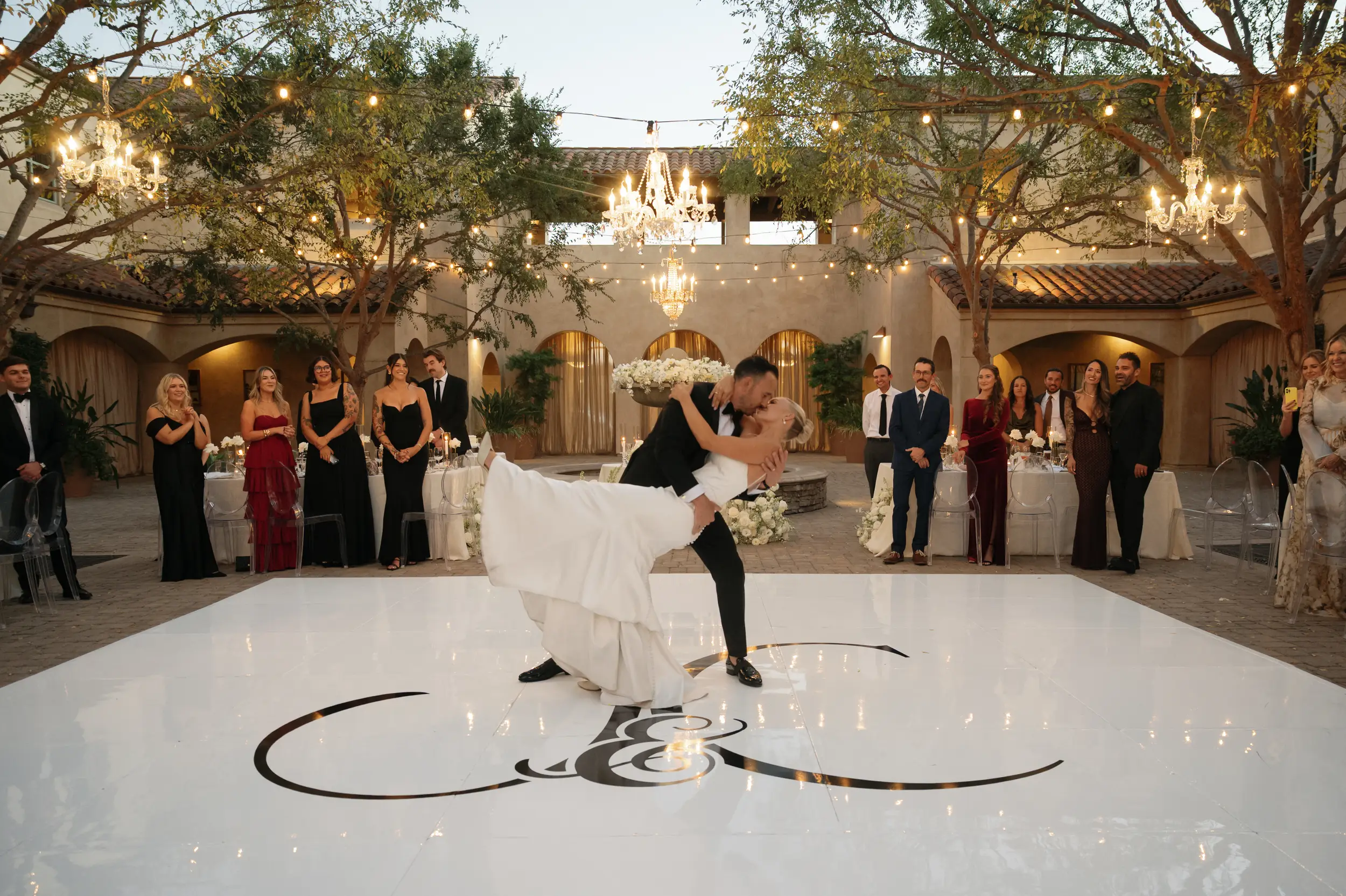 Bride and groom dip for a kiss when their first dance ends and guests cheer from their seats.r