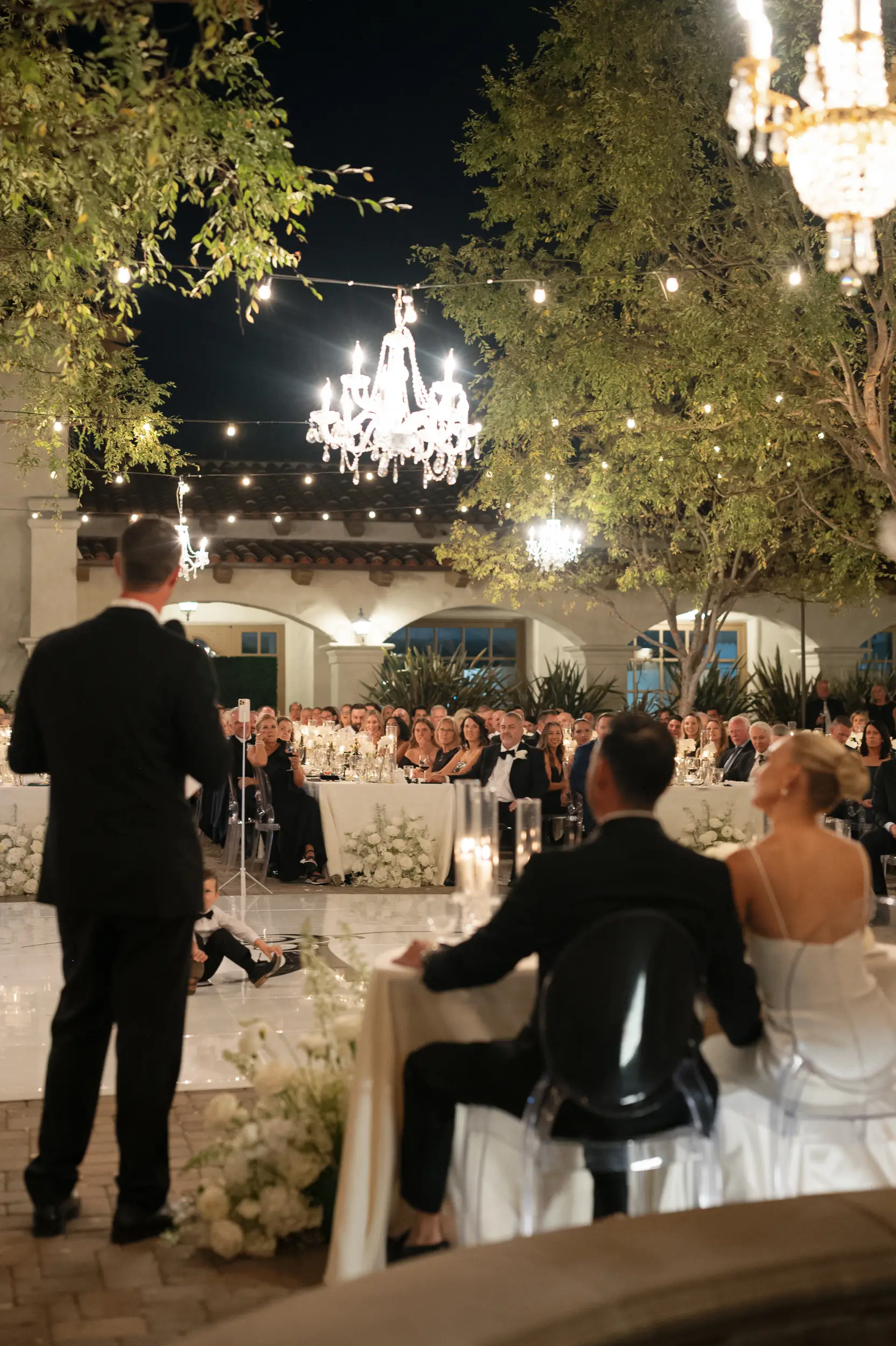 Bride and groom watch as their friend shares a toast.