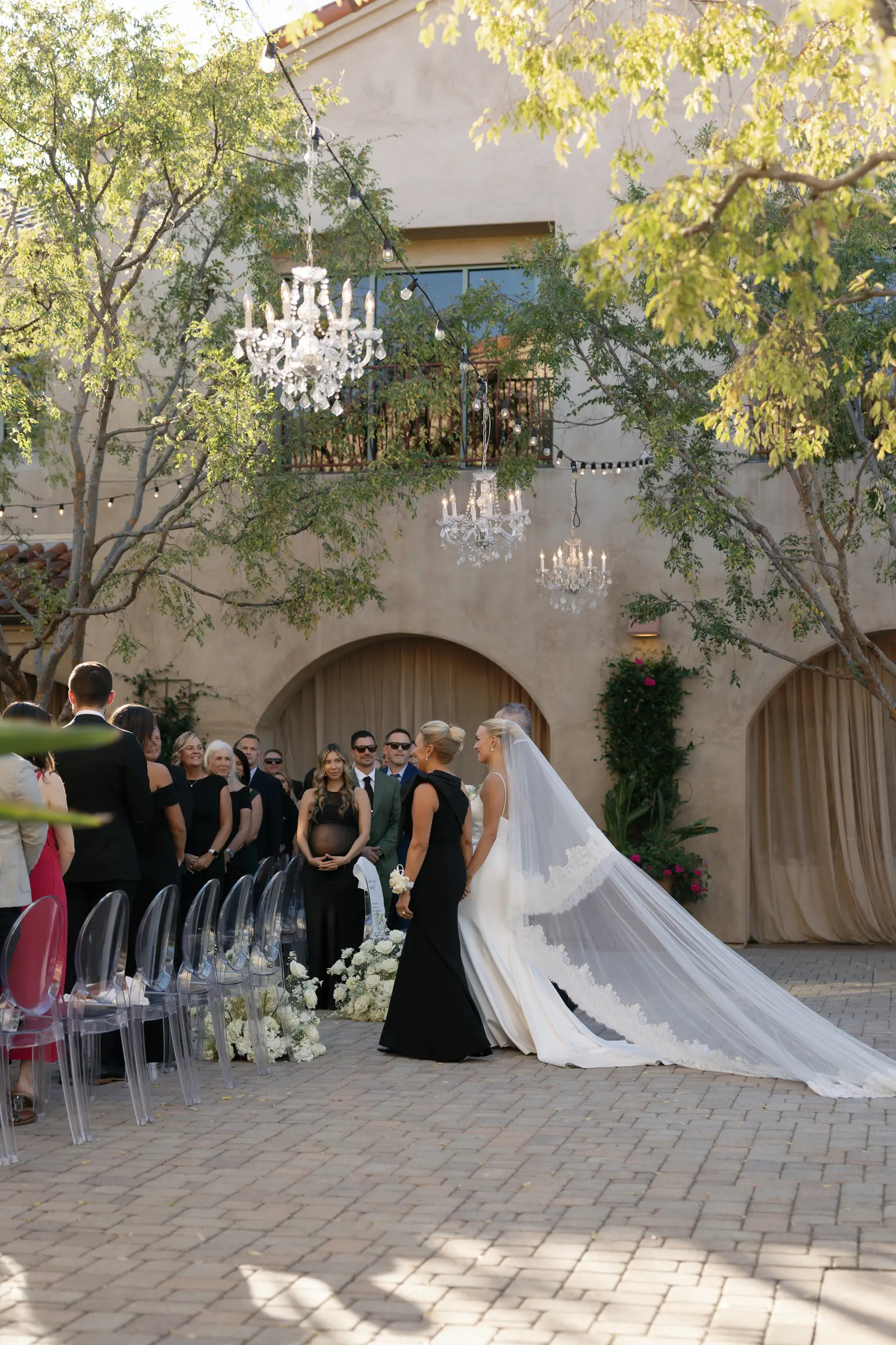 Bride makes ceremony entrance with parents arm-in-arm.