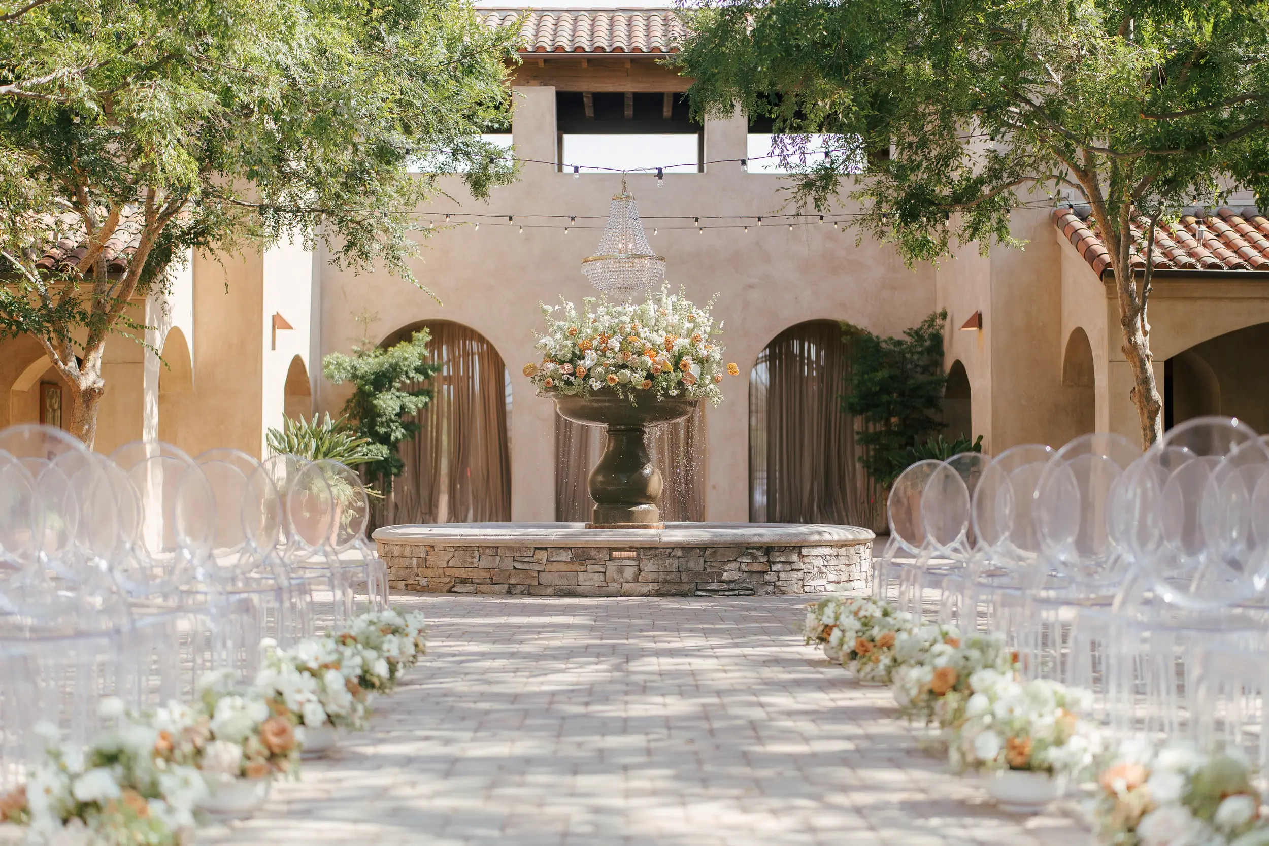 Terracotta wedding florals decorate the courtyard for an outdoor wedding ceremony.
