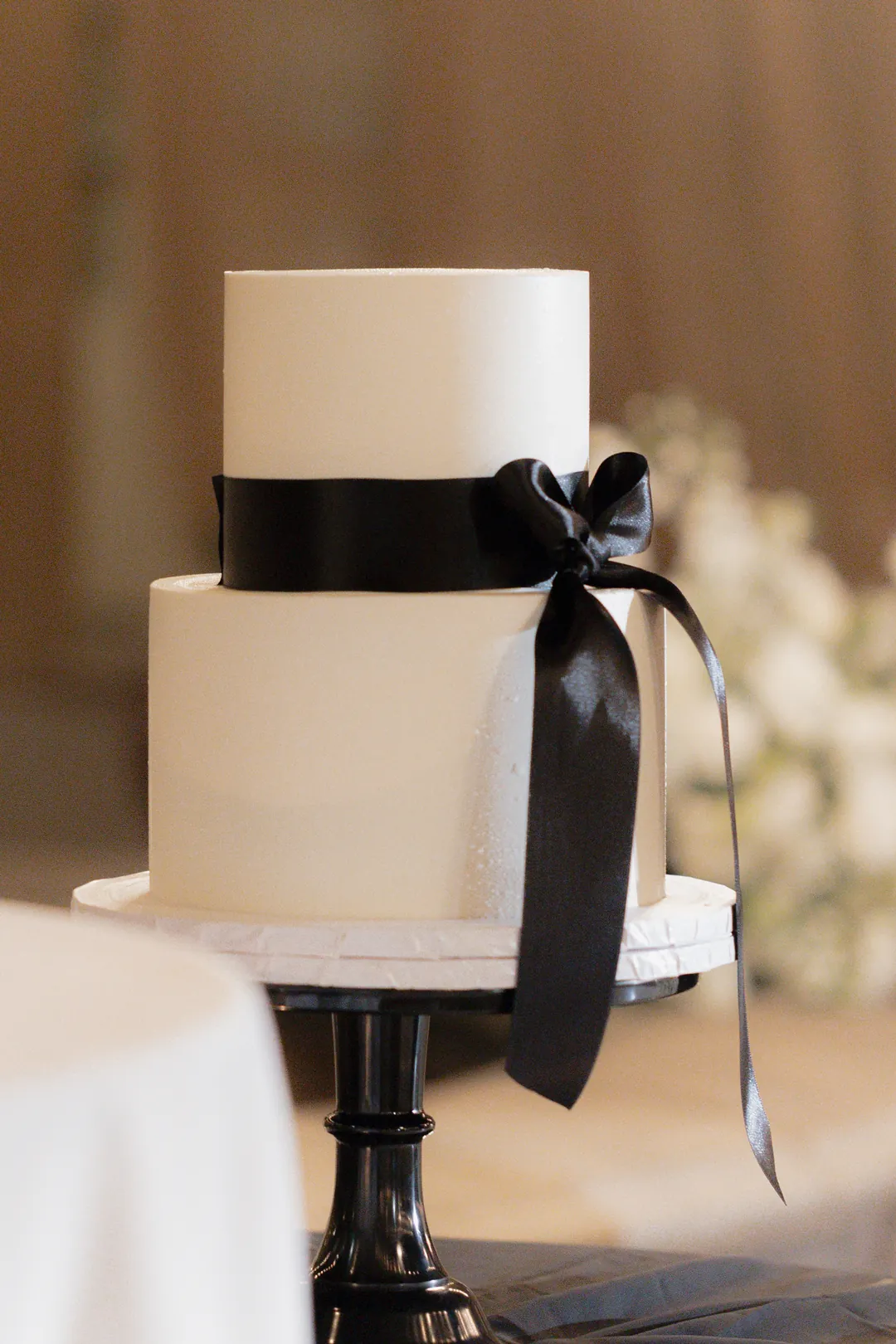 White flat iced wedding cake with black bow detail.