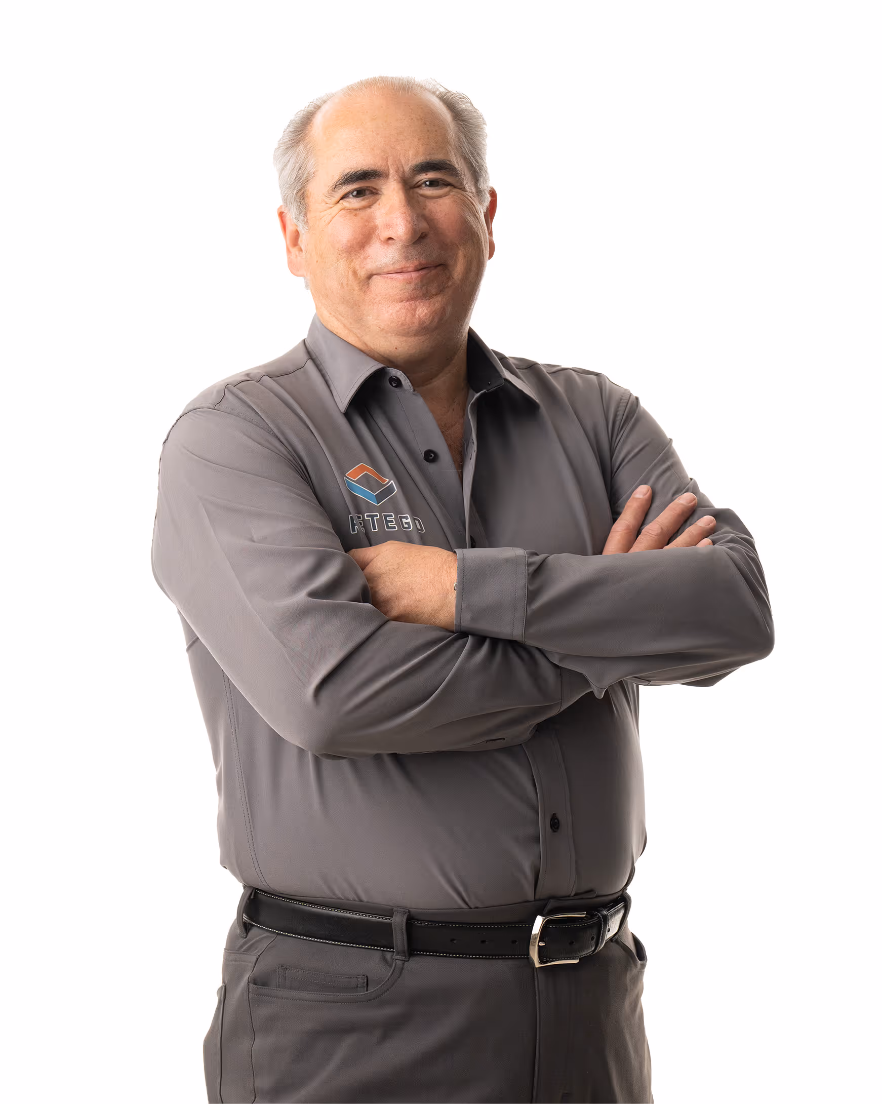 Les Merrill smiling with arms crossed wearing a gray button-up shirt with a Retego logo.