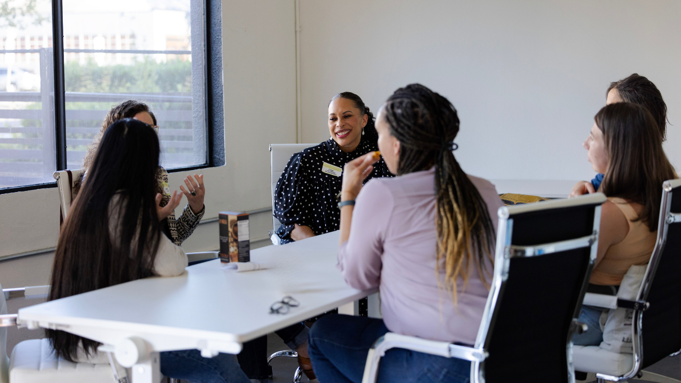 6 business women chatting around a desk