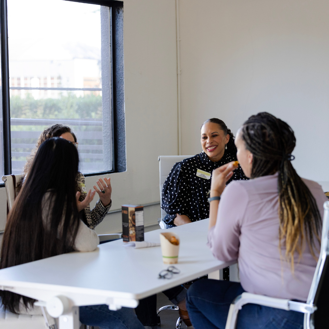 6 business women chatting around a desk