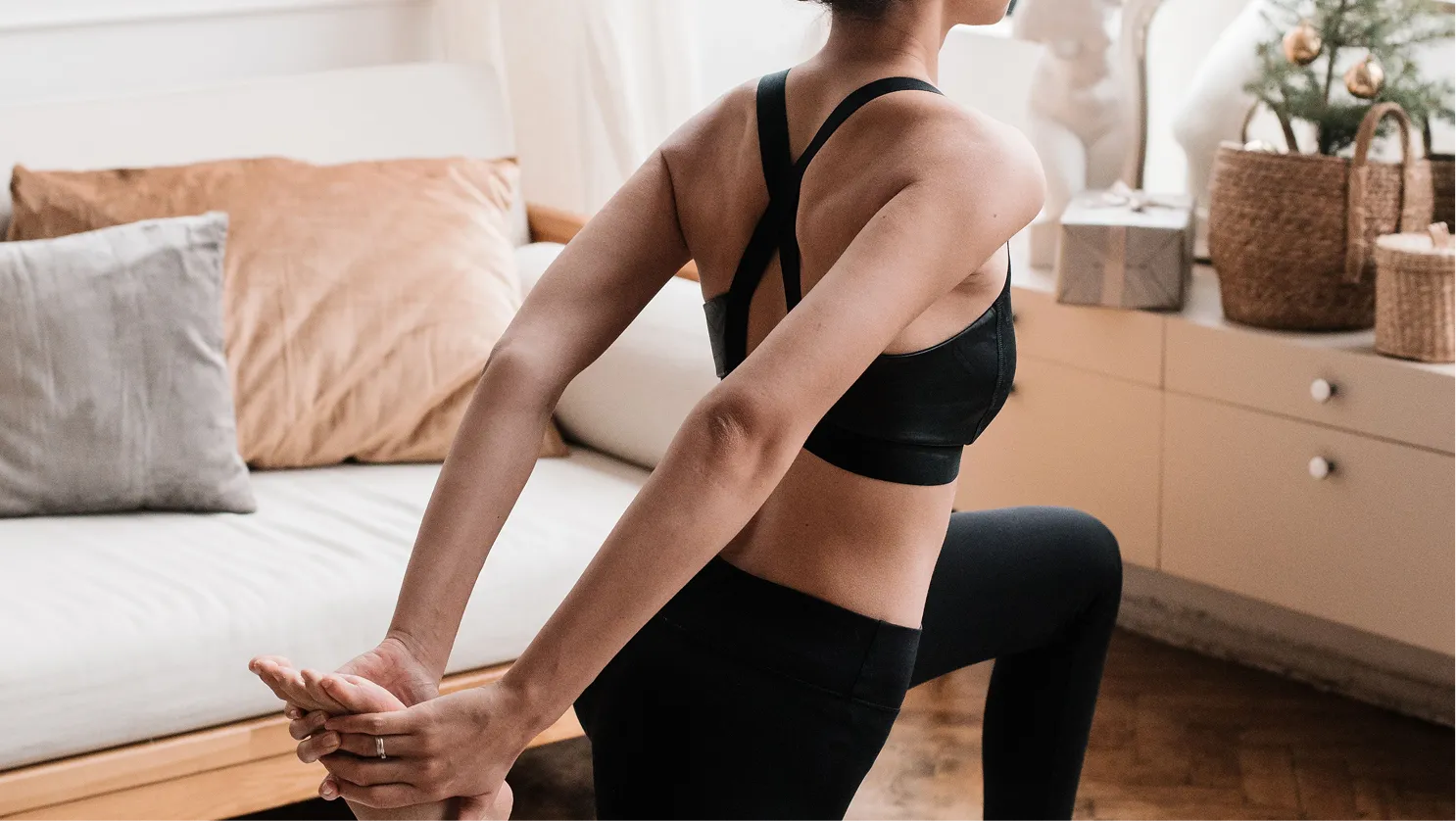 Femme qui s'étire sur un tapis de yoga à la maison, pour illustrer l'entraînement adapté aux phases du cycle menstruel