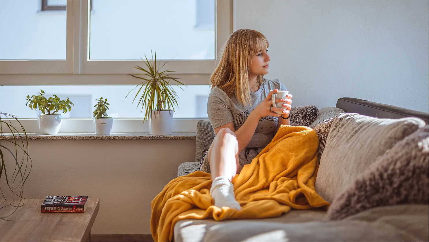 Femme assise sur un canapé avec une tasse de thé