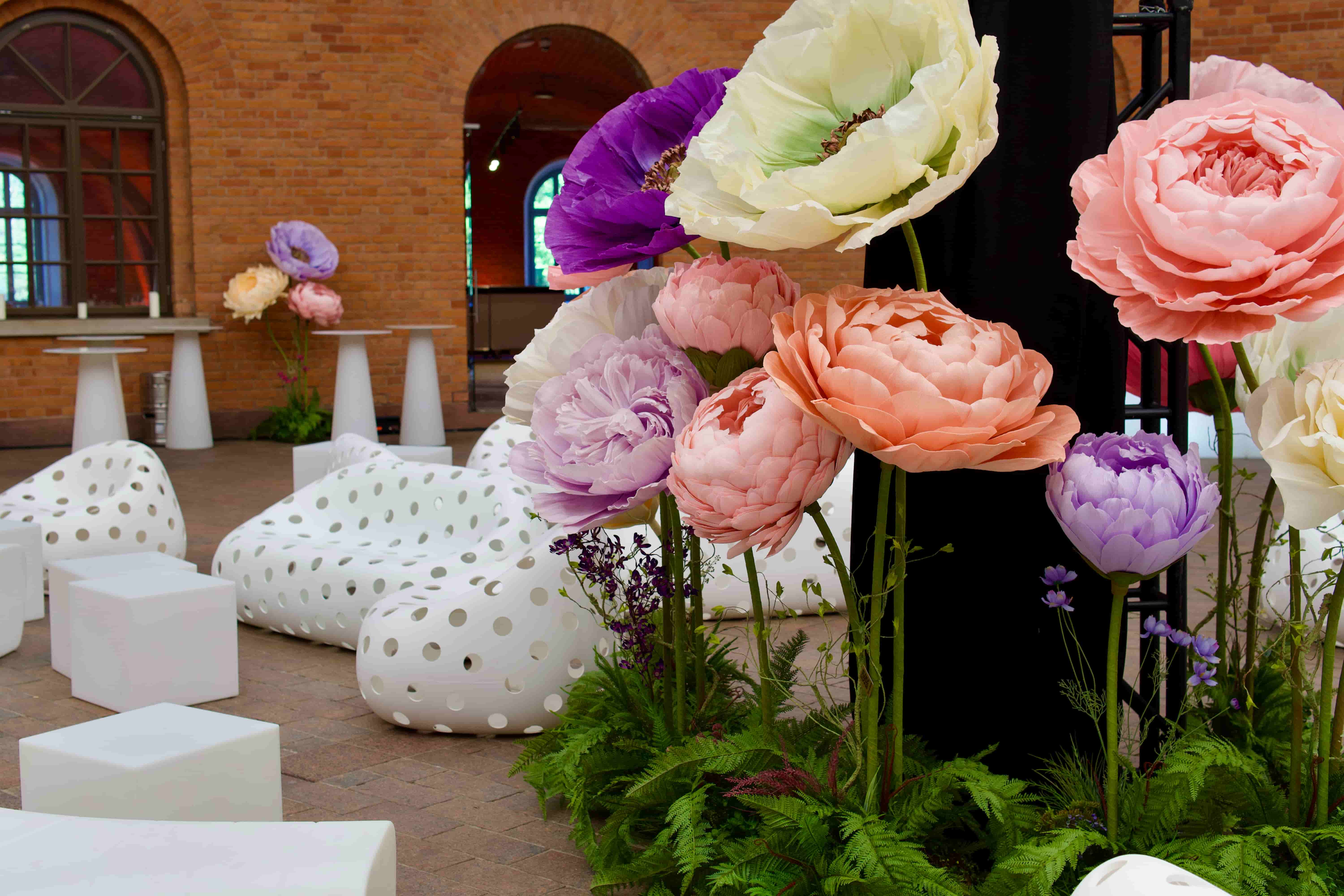 Interior with large colorful artificial flowers from Fiori di Matis near white polka-dotted lounge chairs and cubic stools