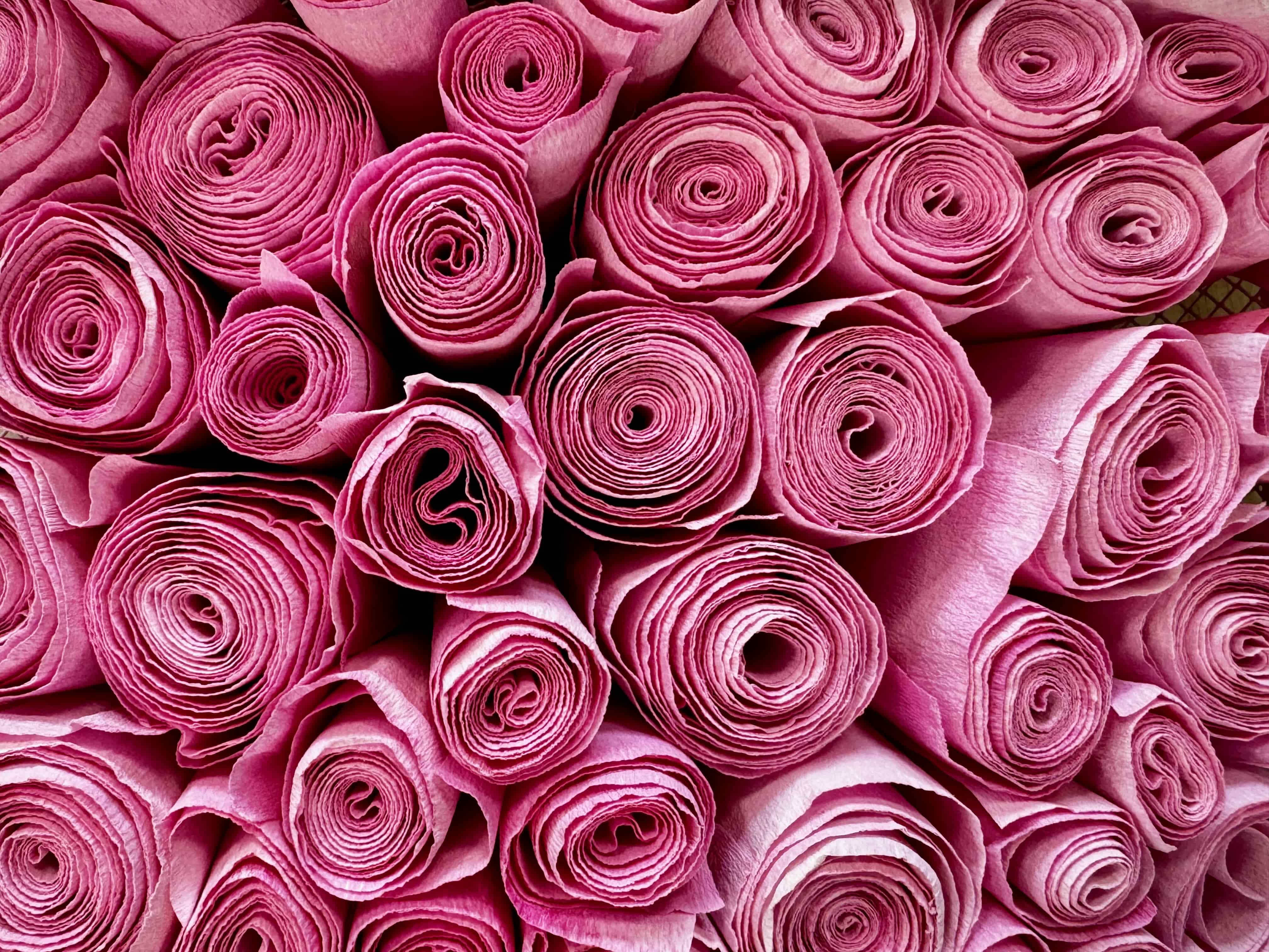 Colorful large artificial flowers of purple, pink, orange, and white against dense green leaves.