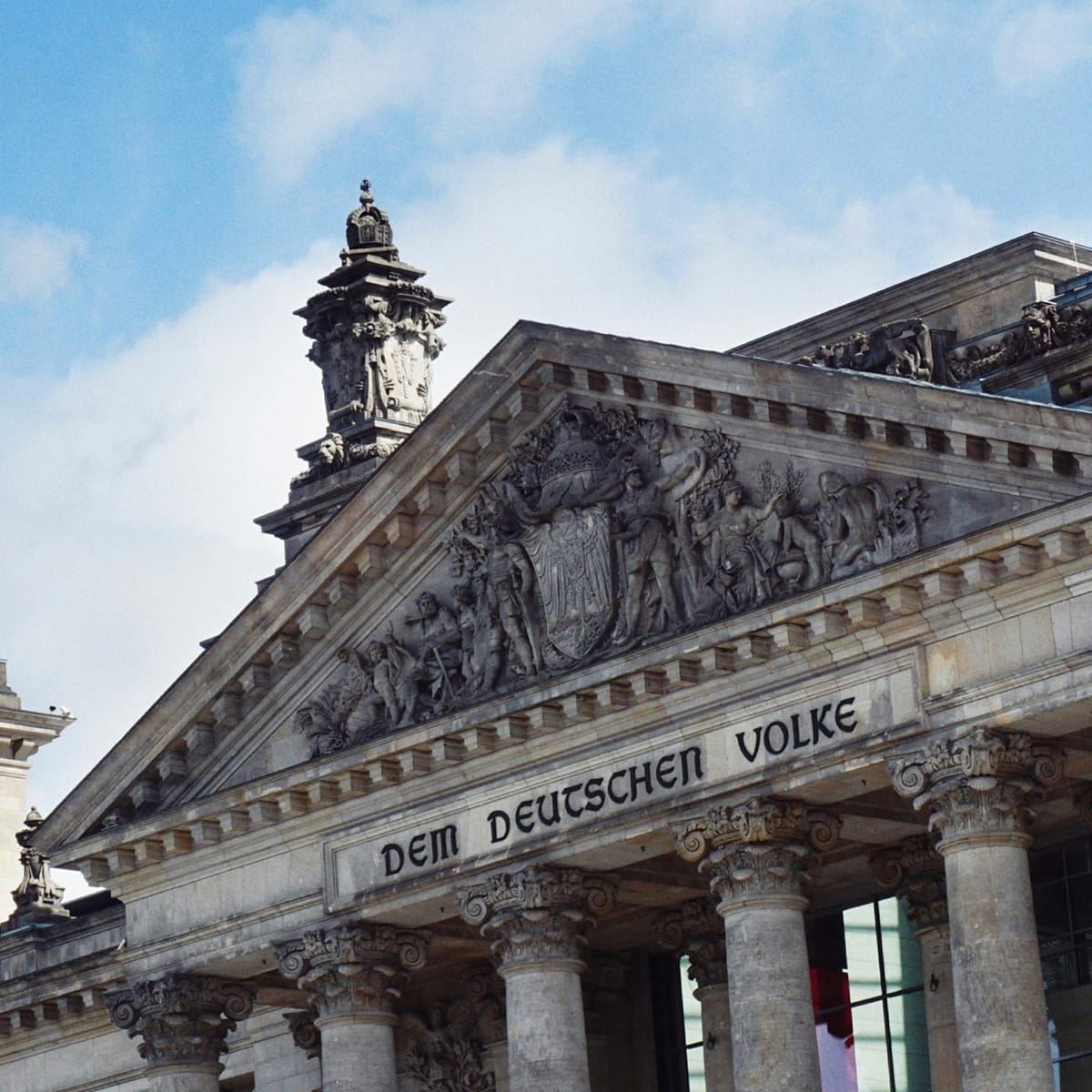 Cropped Photo of the Reichstag building in Berlin, home of the German parliament, the Bundestag. The writing on the building says "Dem Deutschen Volke" (for the German people).
Copyright for the photo: Maheshkumar Painam on Unsplash.