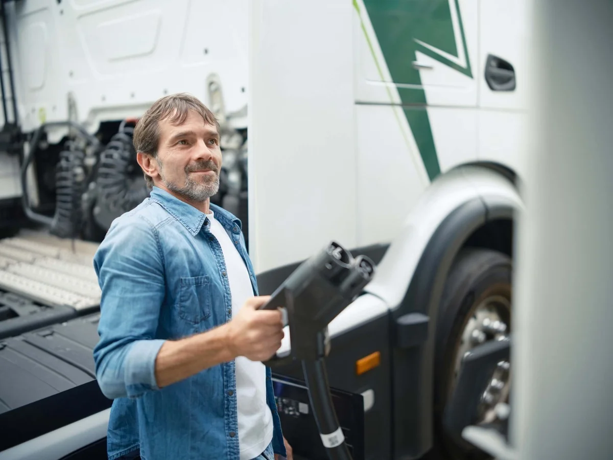 Un camion électrique blanc en cours de chargement, avec le câble de recharge branché.