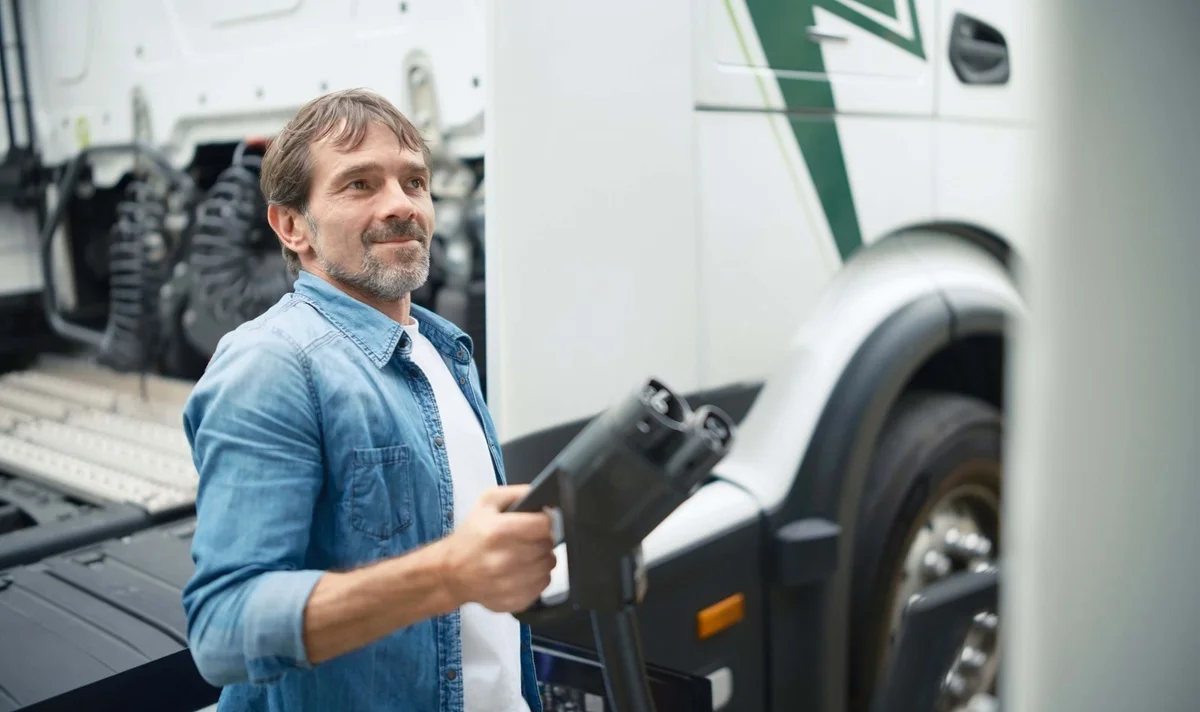 Un camion électrique blanc en cours de chargement, avec le câble de recharge branché.