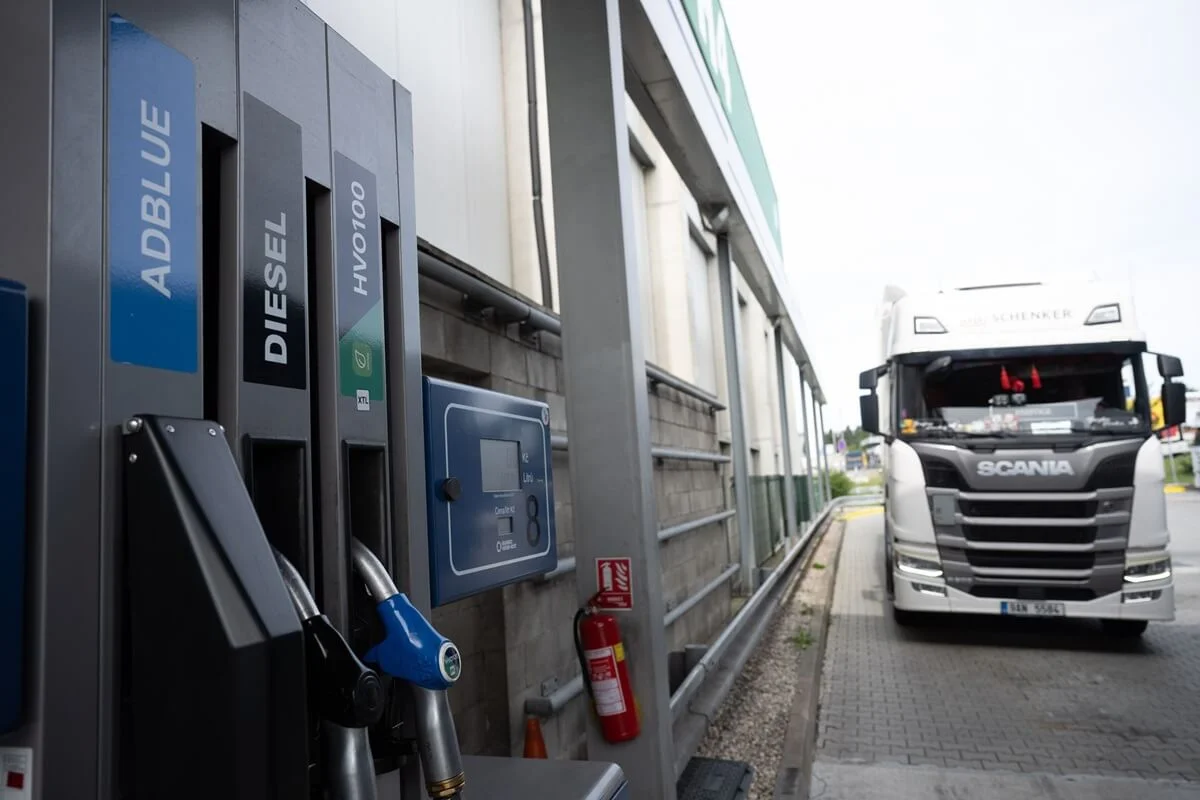 A truck driving down a road toward the horizon, surrounded by open landscape.