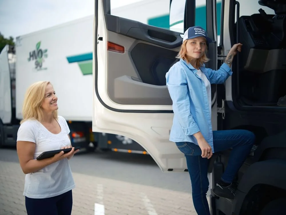 Two men in a truck park focused on viewing content on a tablet.