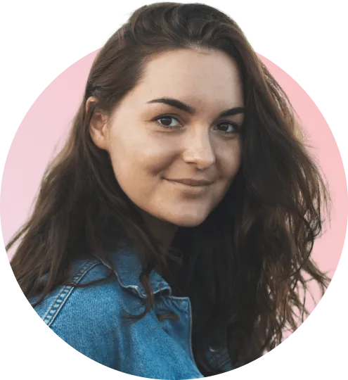 A woman with long hair and a blue denim jacket smiling in a pink circle.