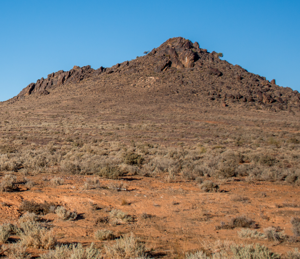 Grassland below a low rocky hill