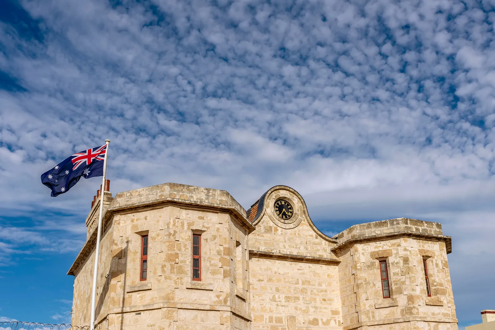 Historic limestone building with an Australian flag