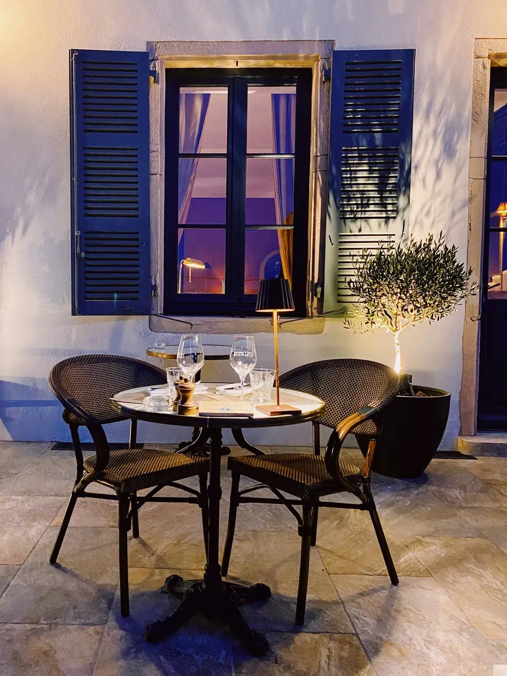 Table romantique dressée en terrasse au crépuscule, dans un village du Beaujolais, avec verres de vin et ambiance chaleureuse.
