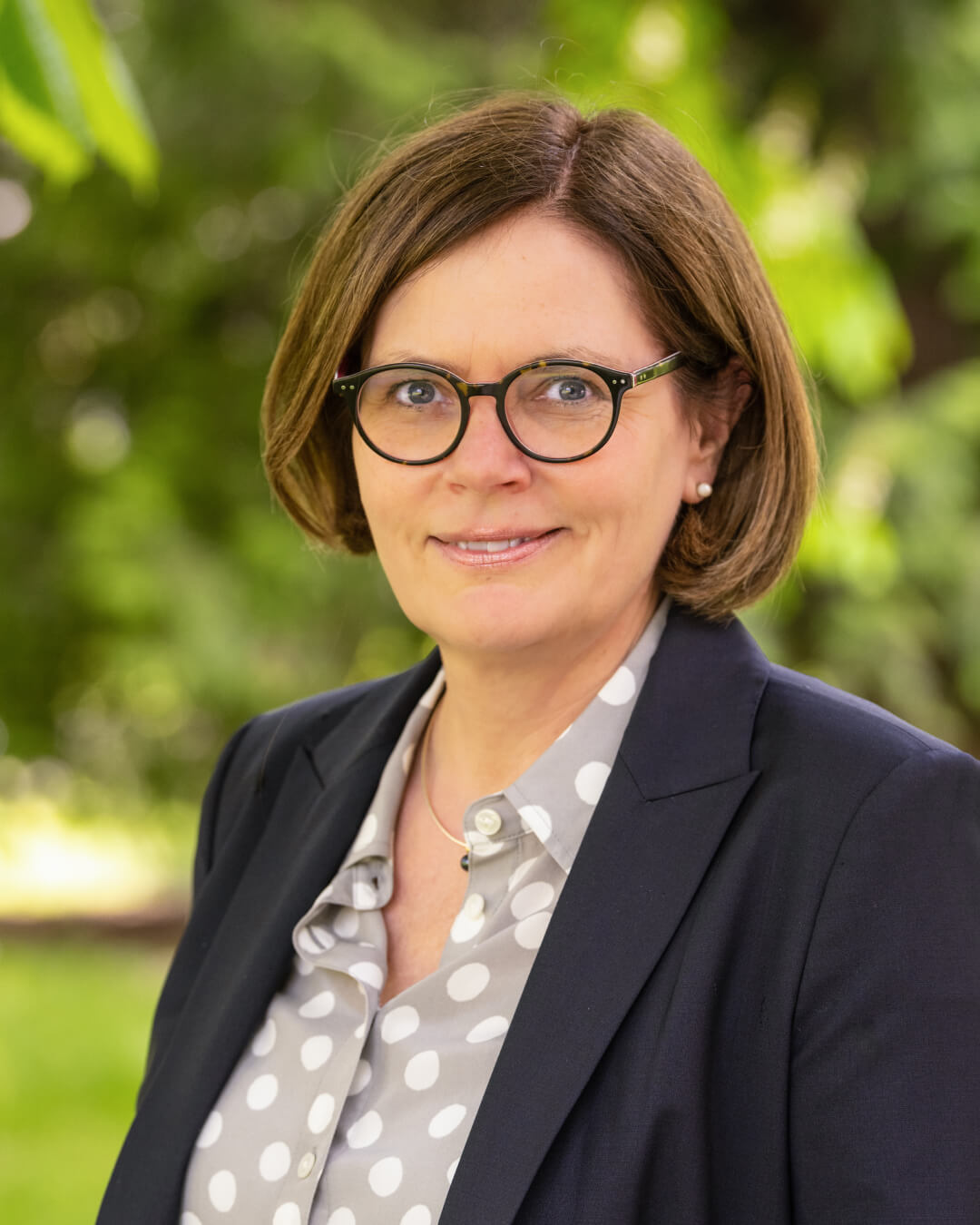 Professional woman in glasses and polka dot shirt smiling outdoors