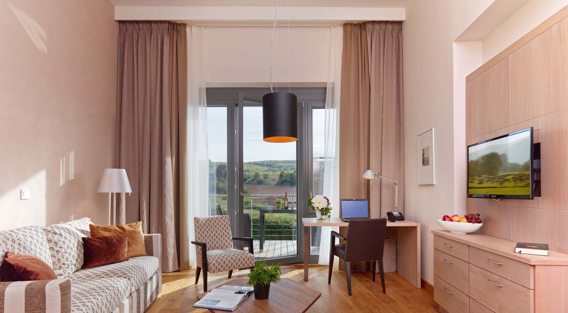 Modernes Hotelzimmer mit Balkon, Arbeitsbereich und Blick auf Landschaft