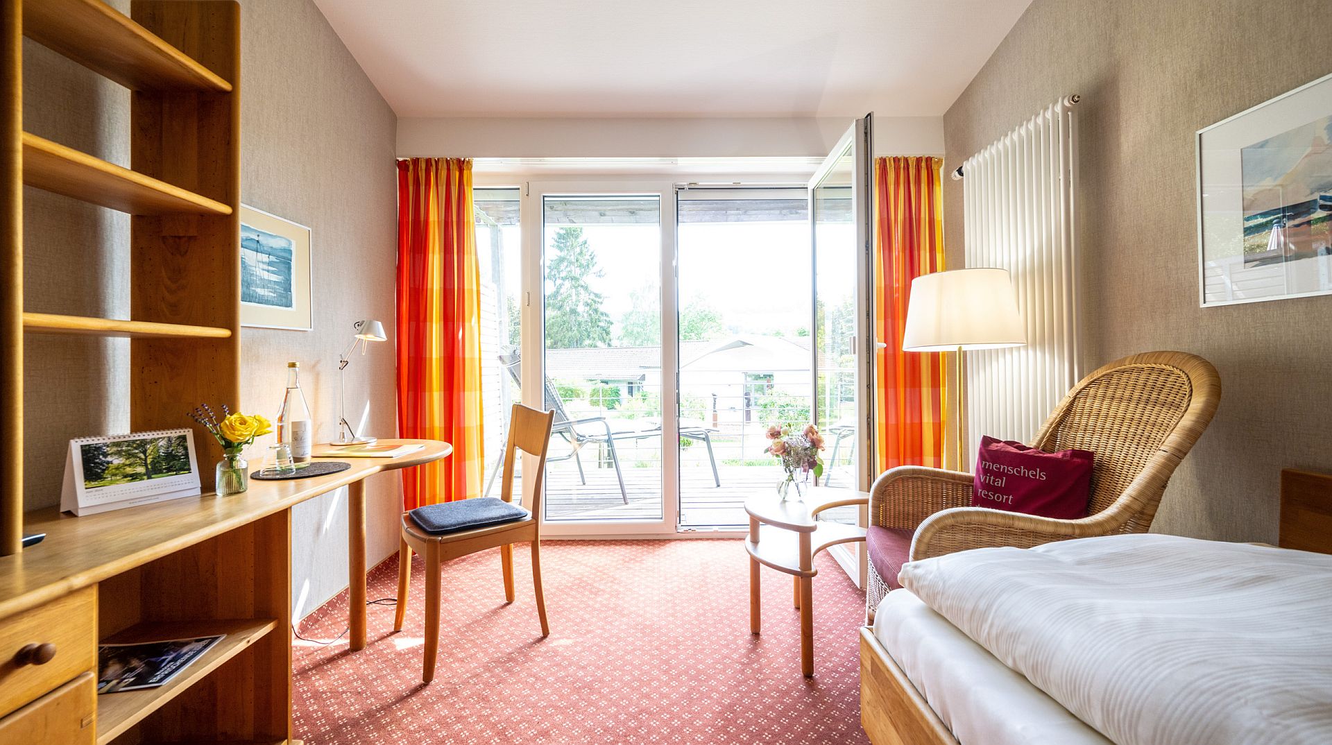 Gemütliches Hotelzimmer mit Rattansessel, Schreibtisch und Terrassenzugang