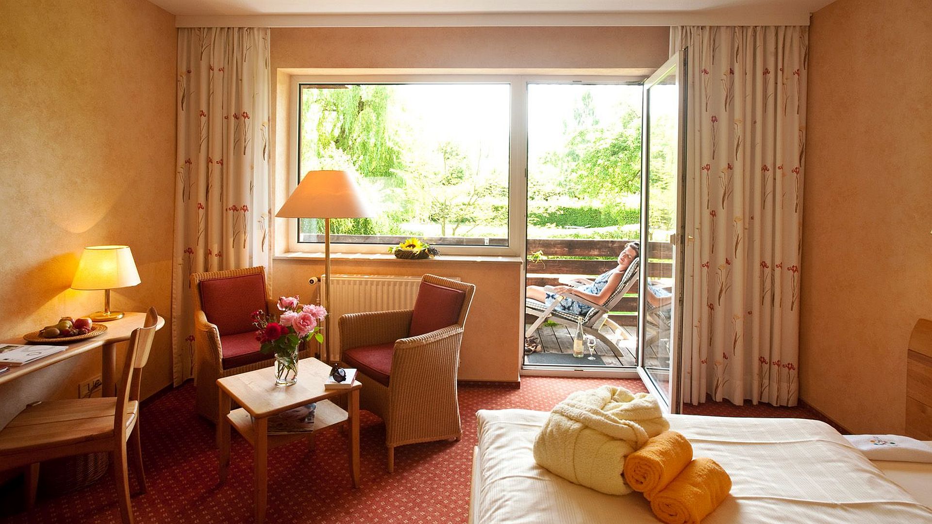 Gemütliches Hotelzimmer mit Balkon, Blumen und Sonnenlicht