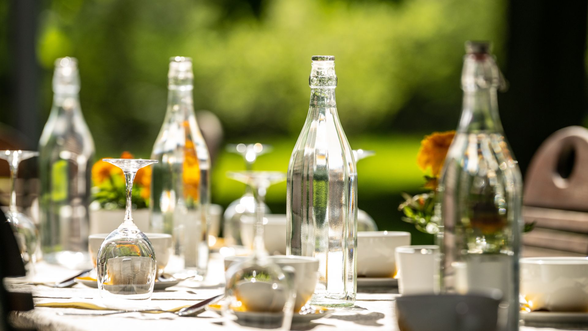 Gedeckter Tisch mit Glasflaschen und Geschirr im Freien an einem sonnigen Tag