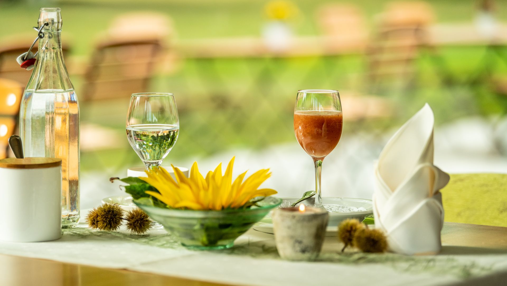 Sommerliche Tischdekoration mit Sonnenblume, Getränken und Kastanien
