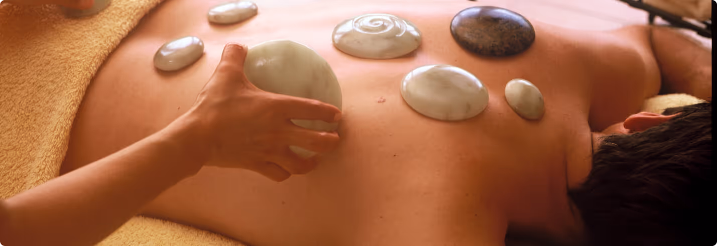 Wellness-Massage mit heißen Steinen auf dem Rücken einer Person