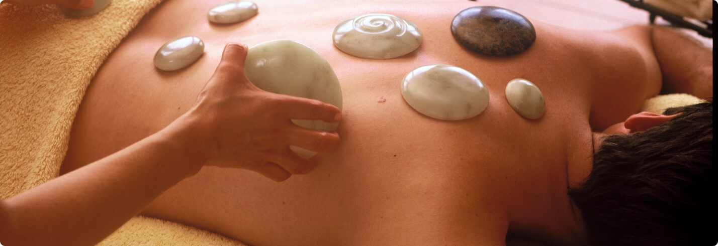 Wellness-Massage mit heißen Steinen auf dem Rücken einer Person