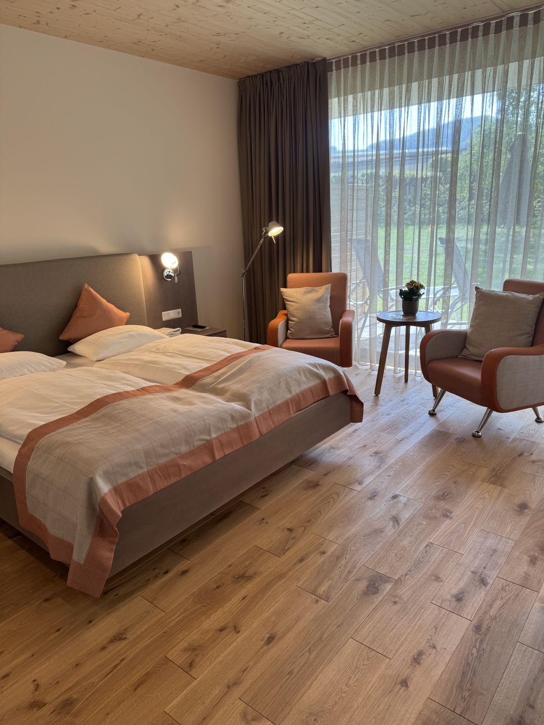 Cozy hotel room with bed, armchairs, and large window overlooking mountains