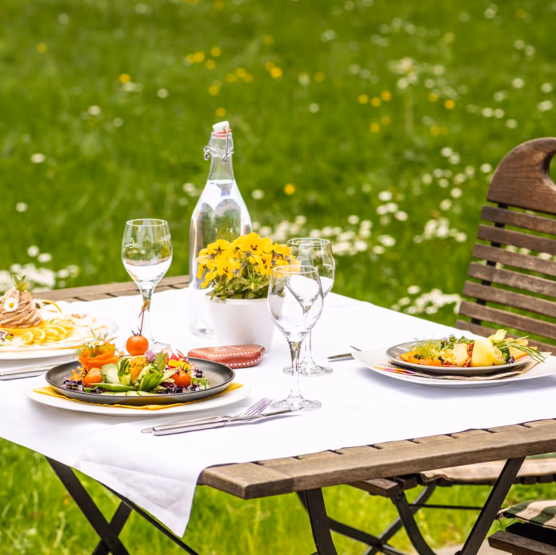 Elegant outdoor dining setup with colorful salads, wine glasses, and flowers