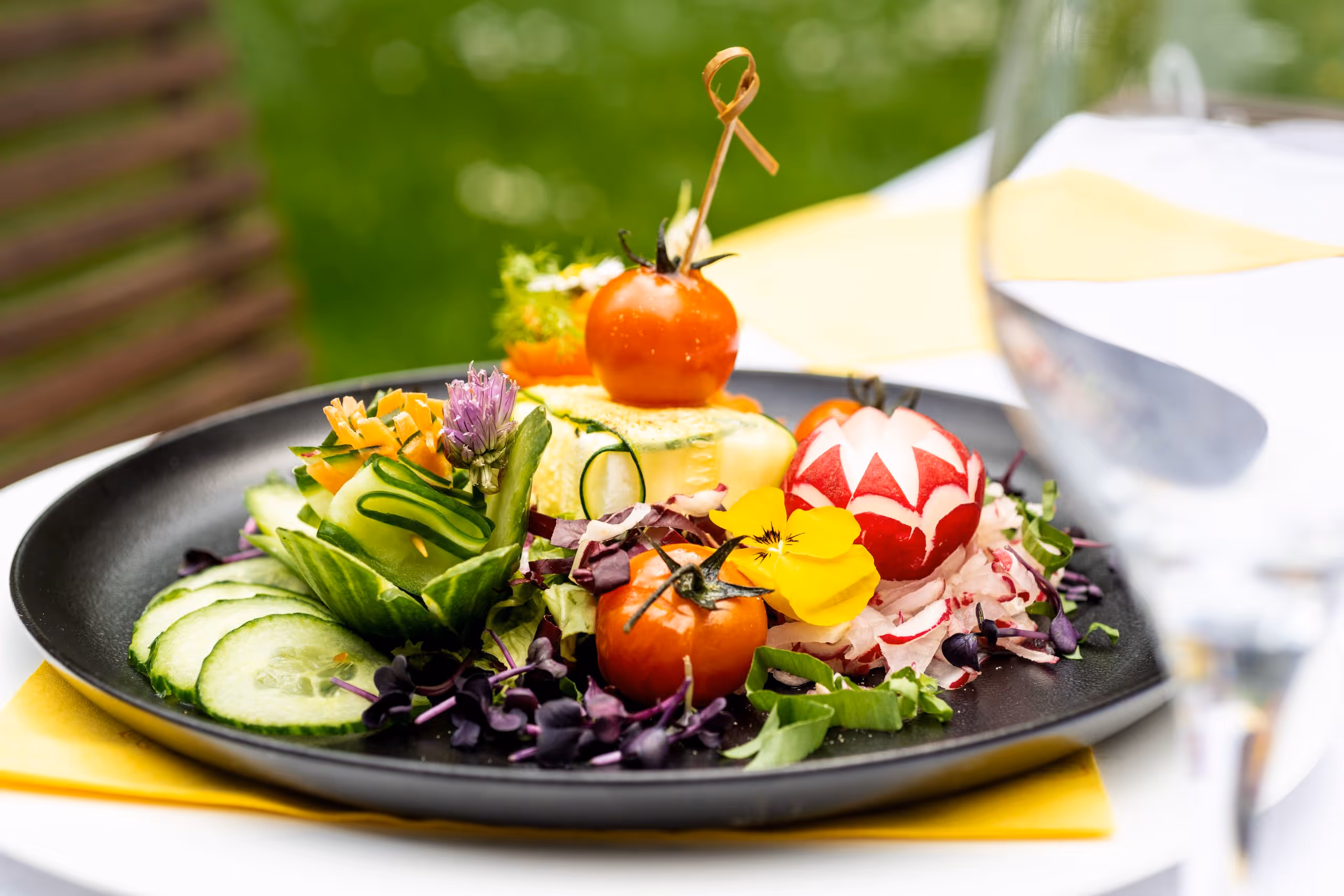 Bunter Salatteller mit Tomaten, Gurken, Blumen und kunstvoller Dekoration