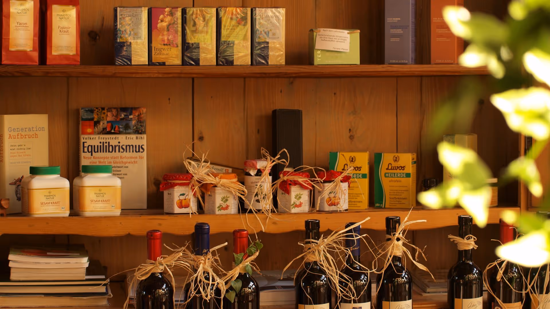 Wooden shelves with books, jars, and wine bottles decorated with raffia