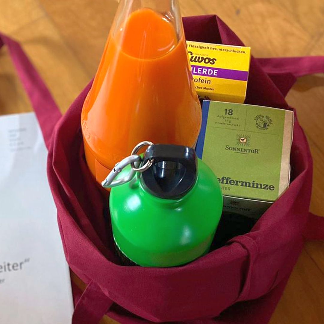 Orange and green bottles with tea box in burgundy fabric bag