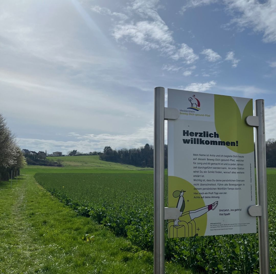 Willkommenstafel auf einem grünen Feld mit Bewegungs-Gesundheitspfad-Schild