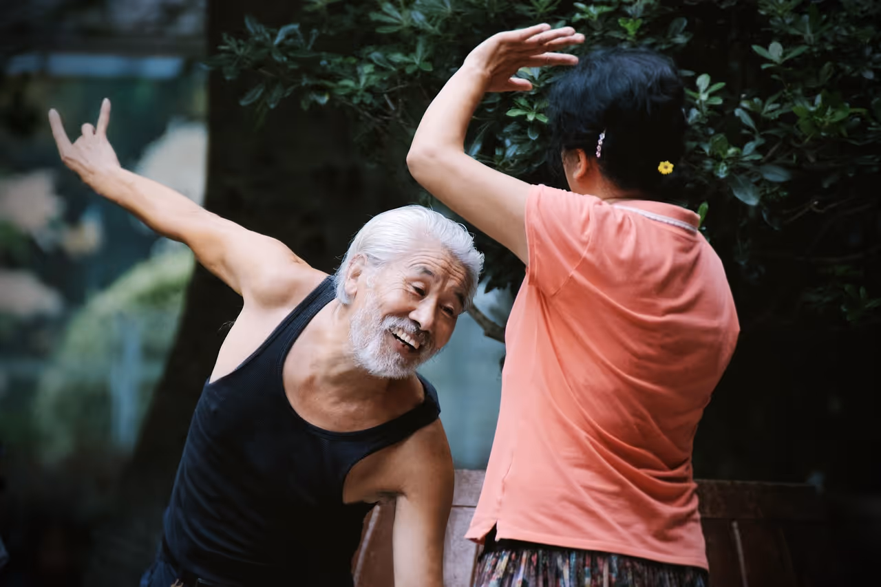 Elderly person dancing joyfully with another person in garden