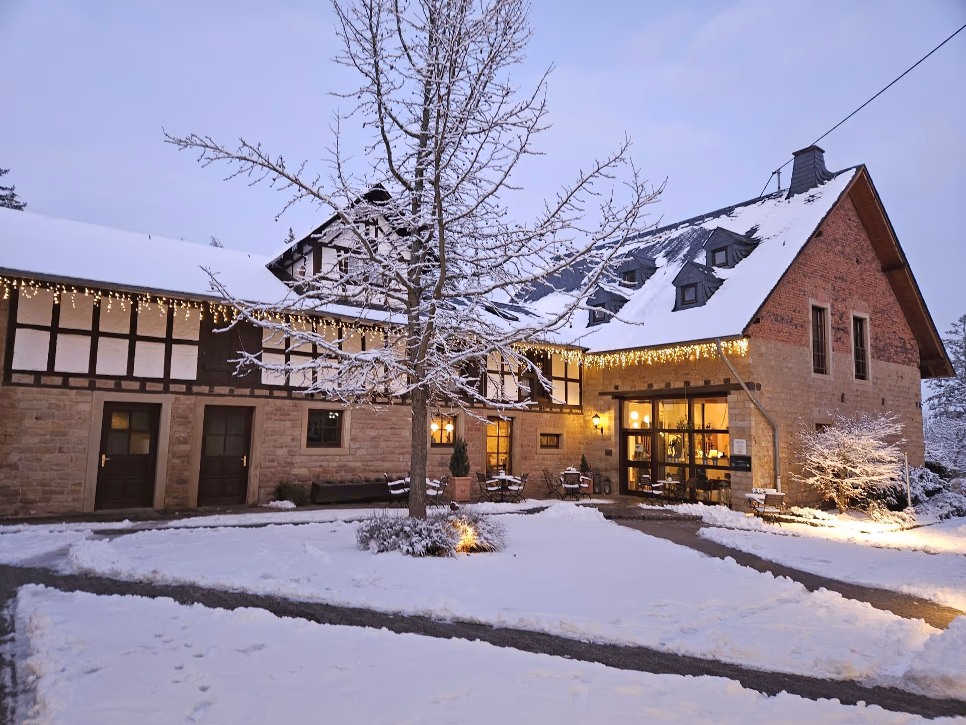 Cozy winter evening, snow-covered house with warm glowing Christmas lights