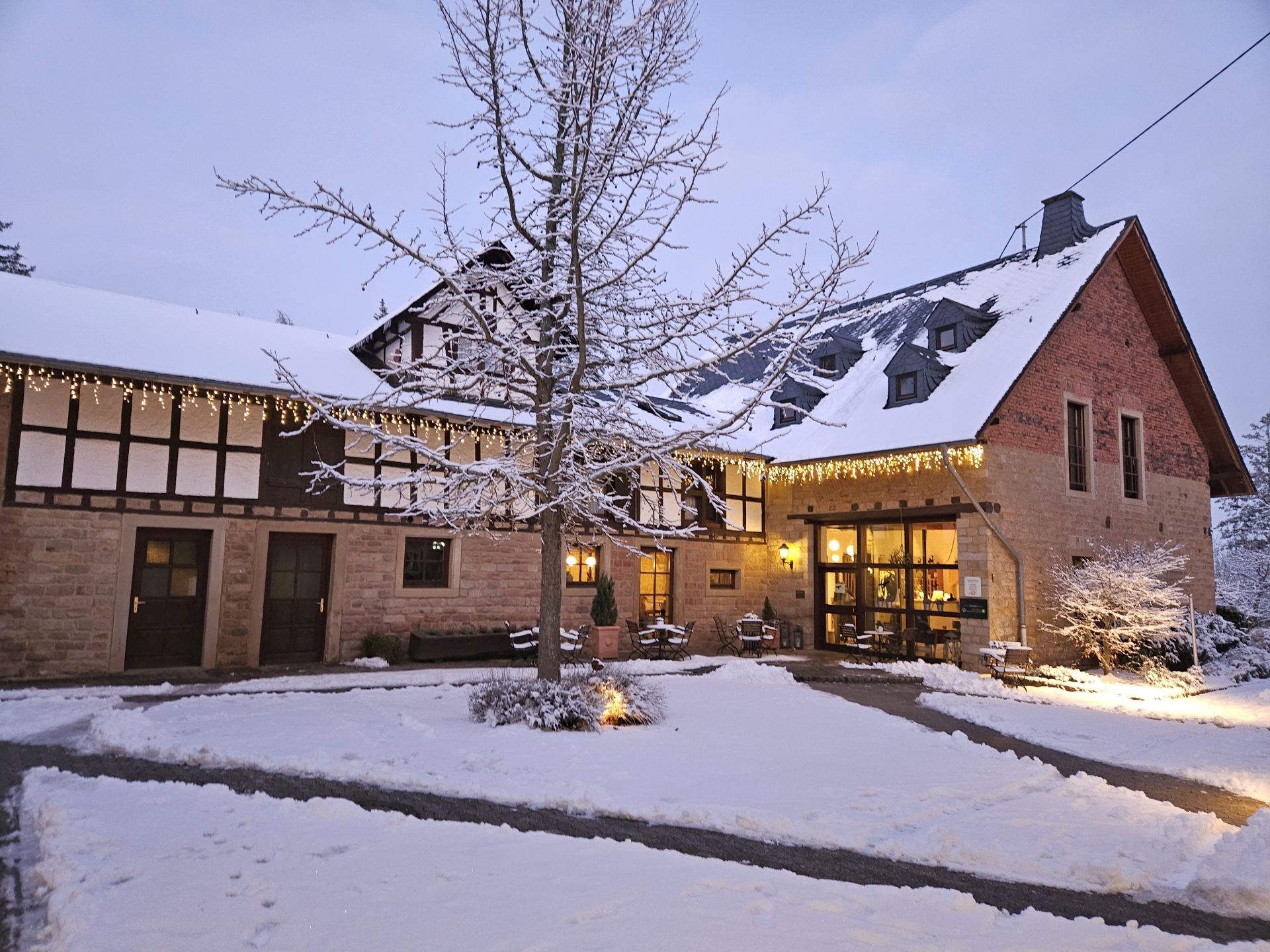 Winterliches Haus mit Schnee und warmem Lichterschein am Abend