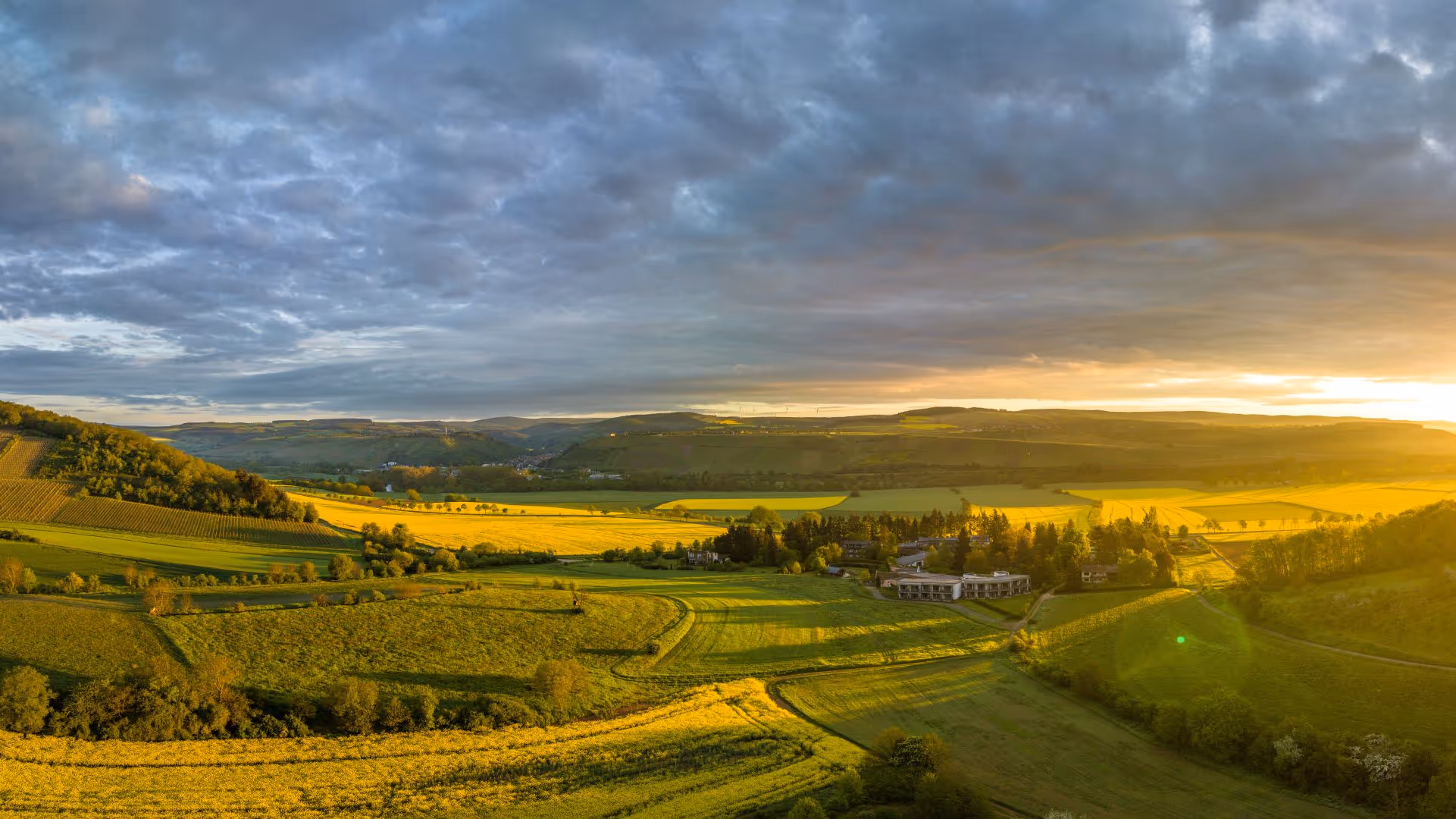 Sonnendurchflutete Landschaft mit grünen Feldern und bewölktem Himmel