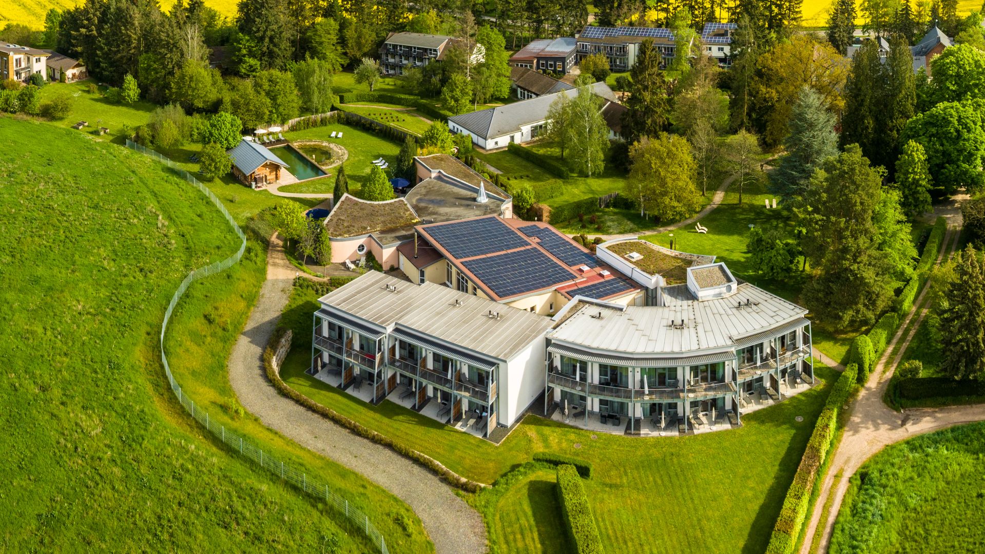 Moderne Wohnanlage mit Solaranlagen, umgeben von grüner Landschaft und Bäumen