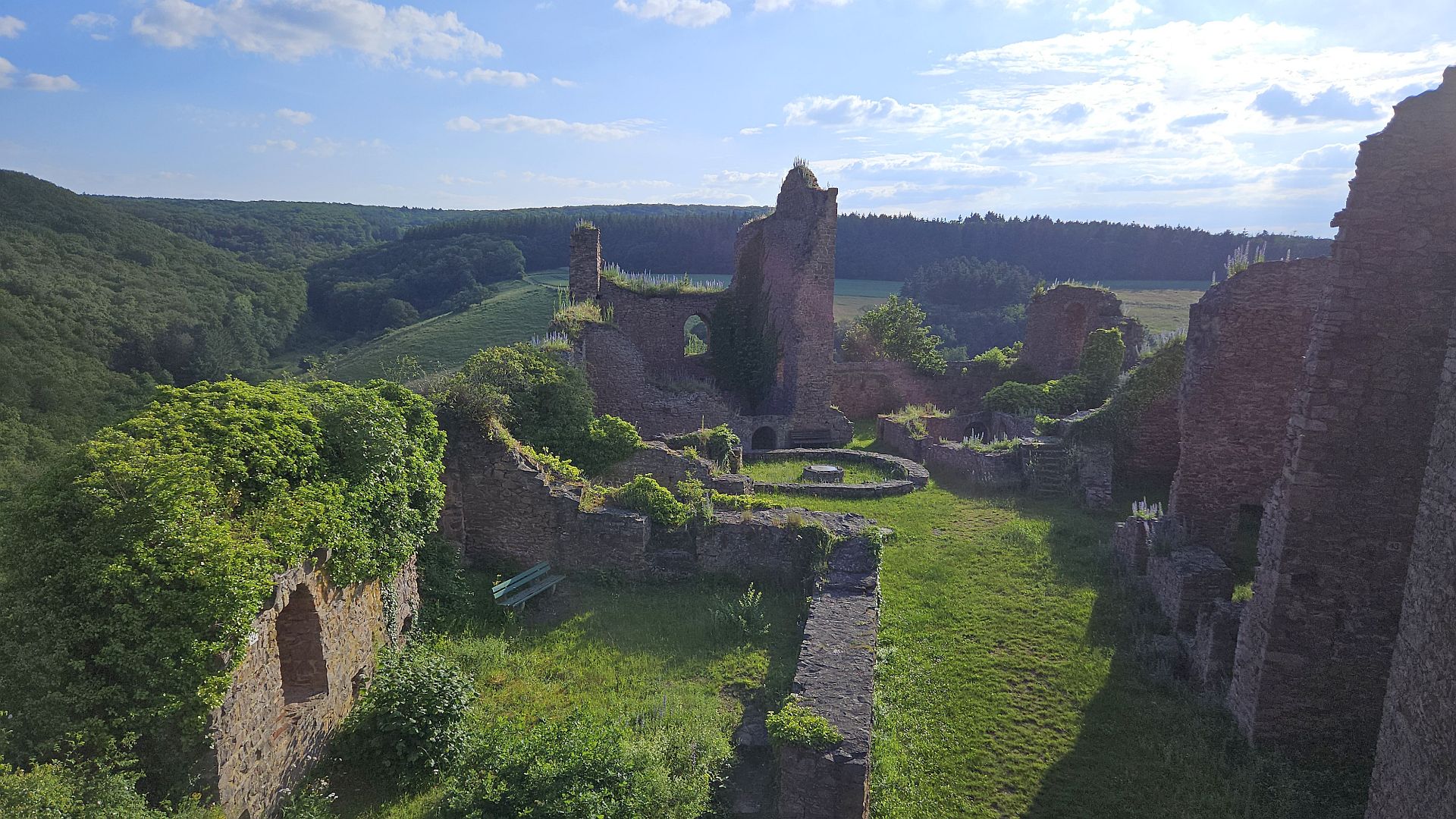 Ancient castle ruins nestled in lush green landscape with forest backdrop