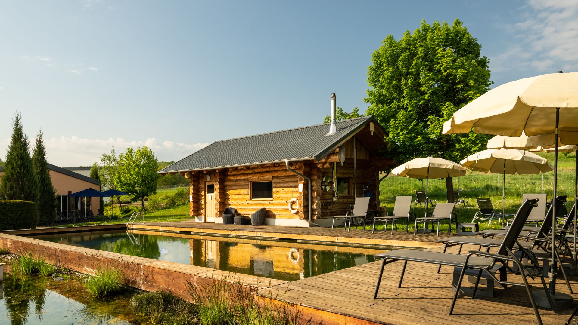 Holzhütte mit Schwimmbad und Liegestühlen in ländlicher Sommerumgebung