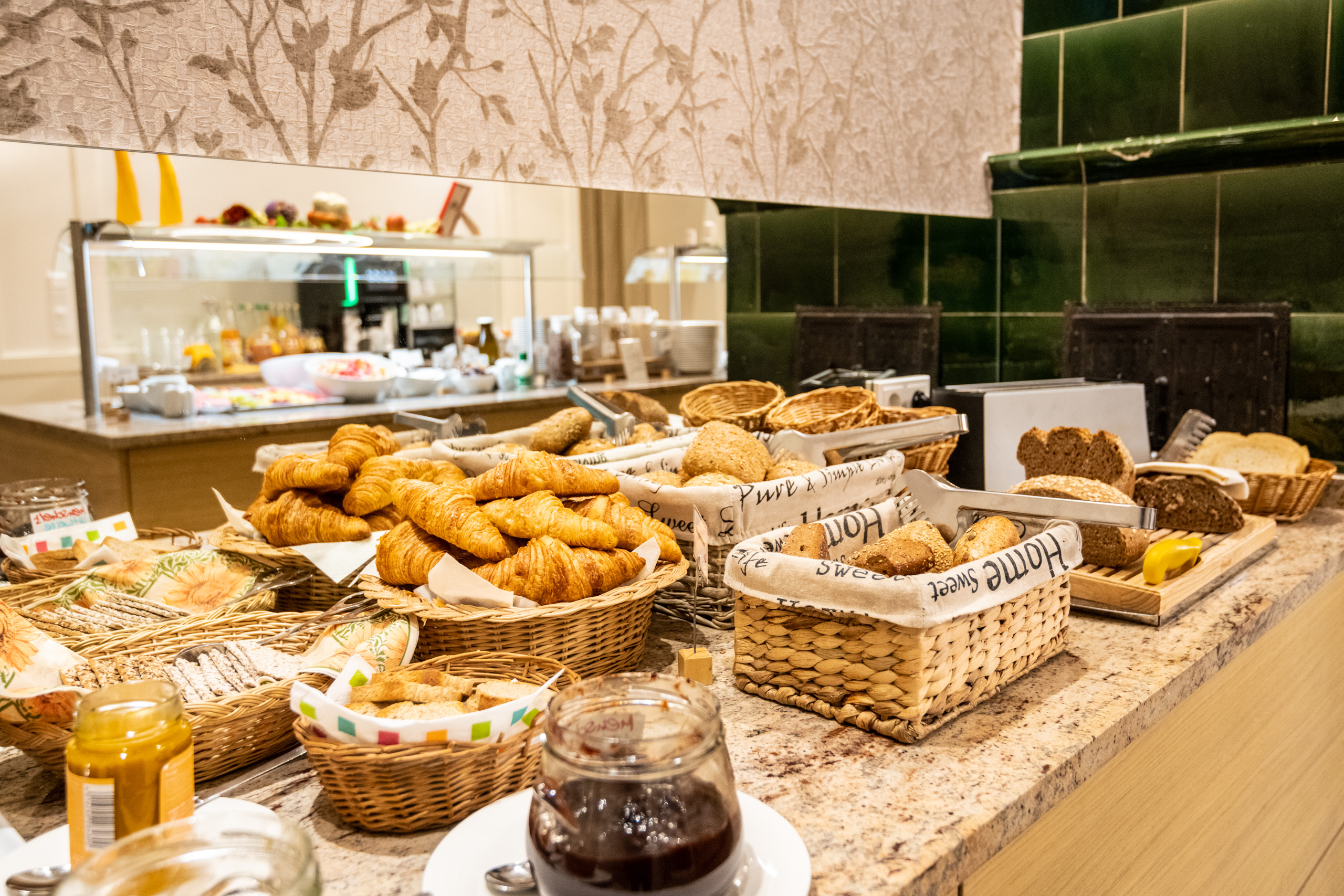Frühstücksbuffet mit Croissants, Brötchen und Marmelade in Körben