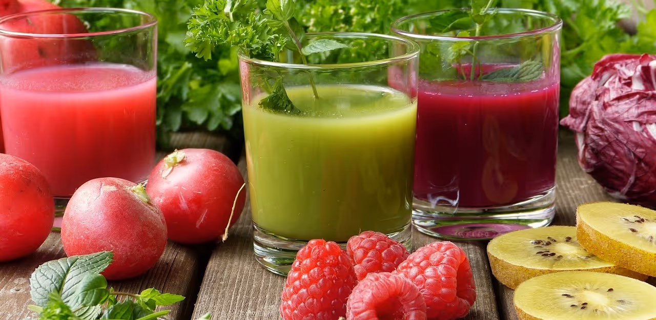 Drei Smoothies mit frischen Früchten und Gemüse auf Holztisch